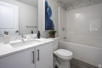 A white bathroom with a toilet, sink, and bathtub.